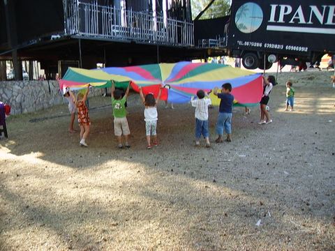 Niños jugando con el paracaídas de colores al aire libre